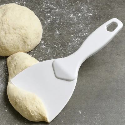 Raspador branco de plástico para massa de pizza, com medidas 21x10 cm.